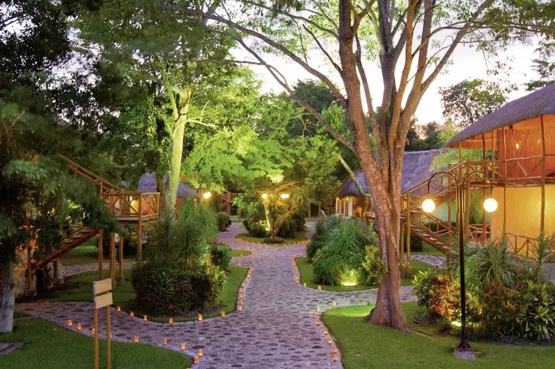 Osvetljene poti skozi tropski vrt Chicanná Ecovillage Resorta ob mraku