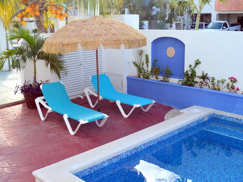 Ležalniki ob bazenu pod slamnatim senčnikom