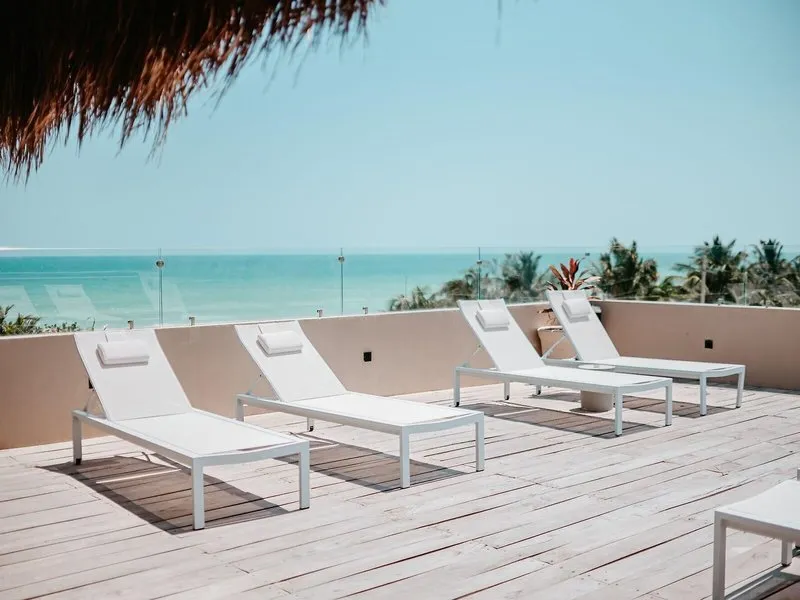 Rooftop terasa z belimi ležalniki in pogledom na morje