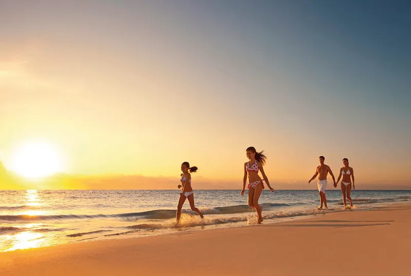 Družina na plaži ob sončnem zahodu