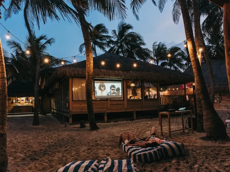 Kino na plaži pod palmami ob večeru