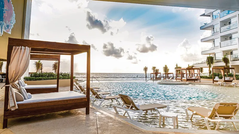 Neskončni bazen s pogledom na ocean in luksuznimi posteljami za sončenje.